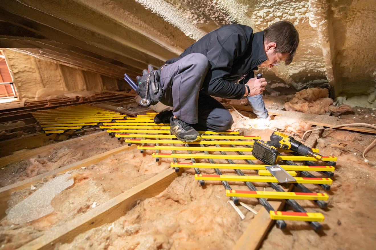 Worker crouched under a low structure with a light, the kind of crawl space access a rat inspection needs